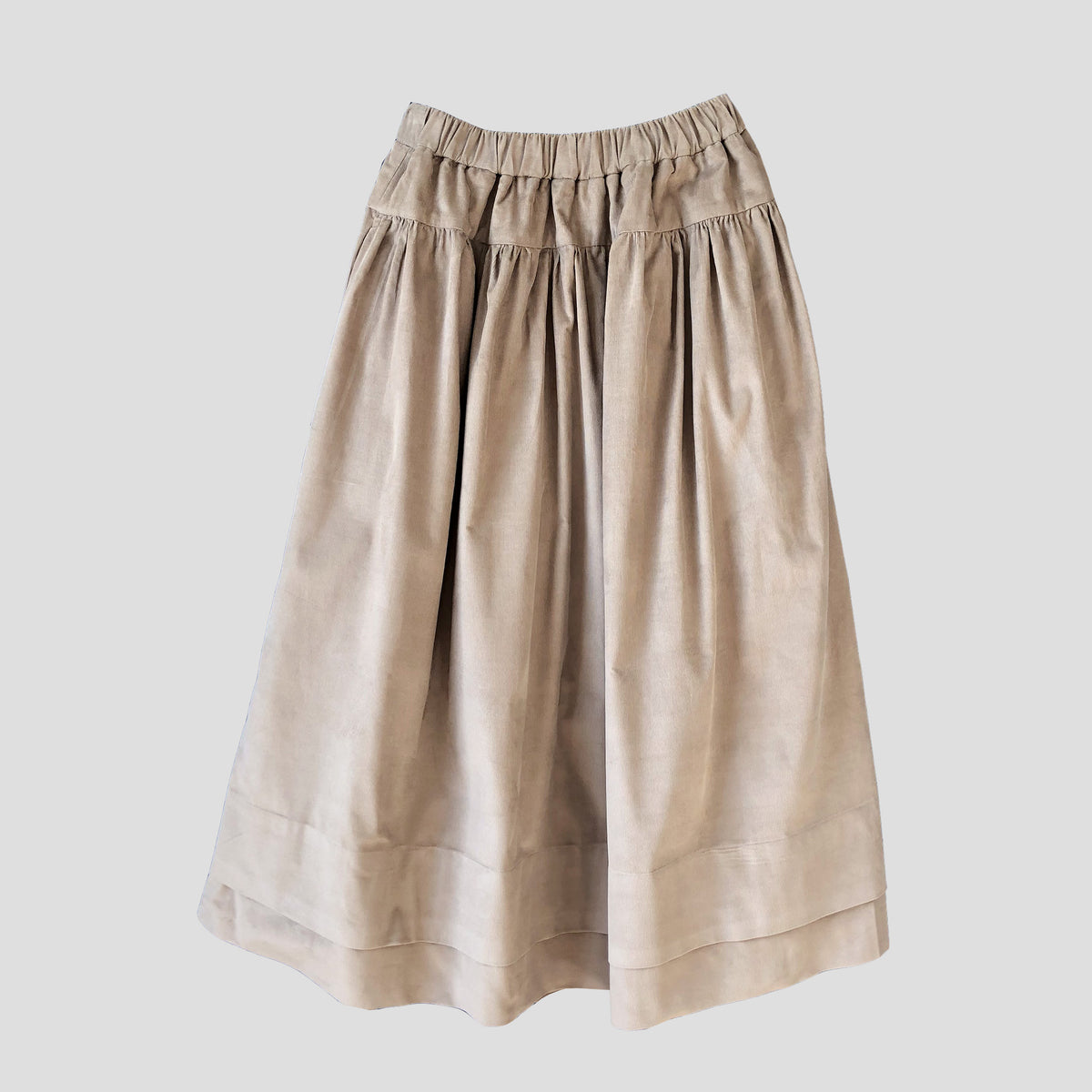 A beige pleated midi skirt with an elastic waistband, shown against a solid light gray background.