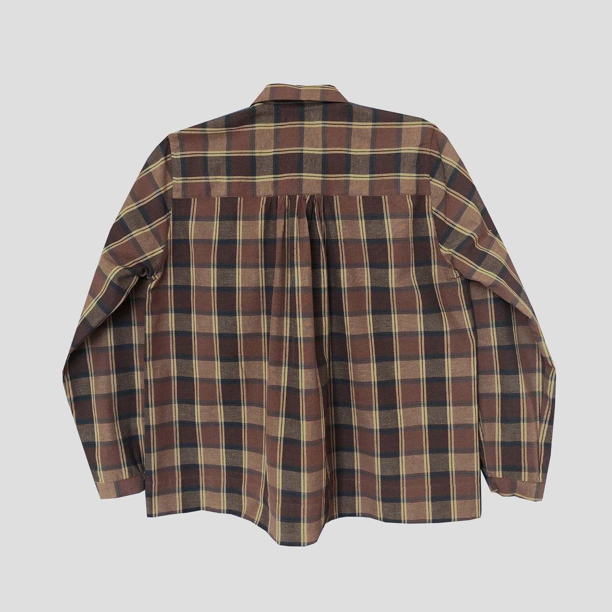 A long-sleeve plaid button-up shirt shown from the back, featuring a brown, beige, and black checkered pattern, laid flat against a solid light gray background.