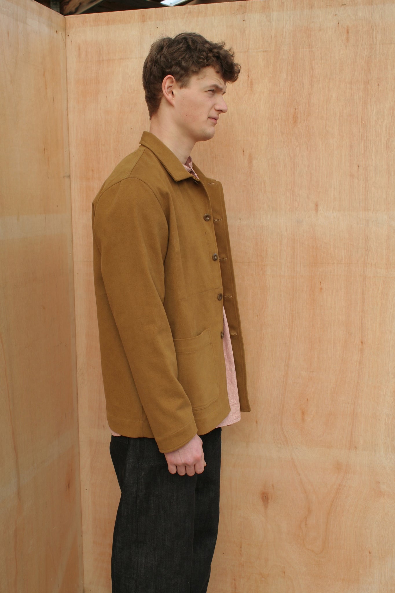 side view of a young man wearing a mustard chore jacket
