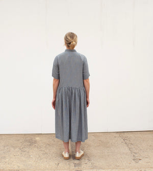 the back view of a blonde woman wearing a gingham dress