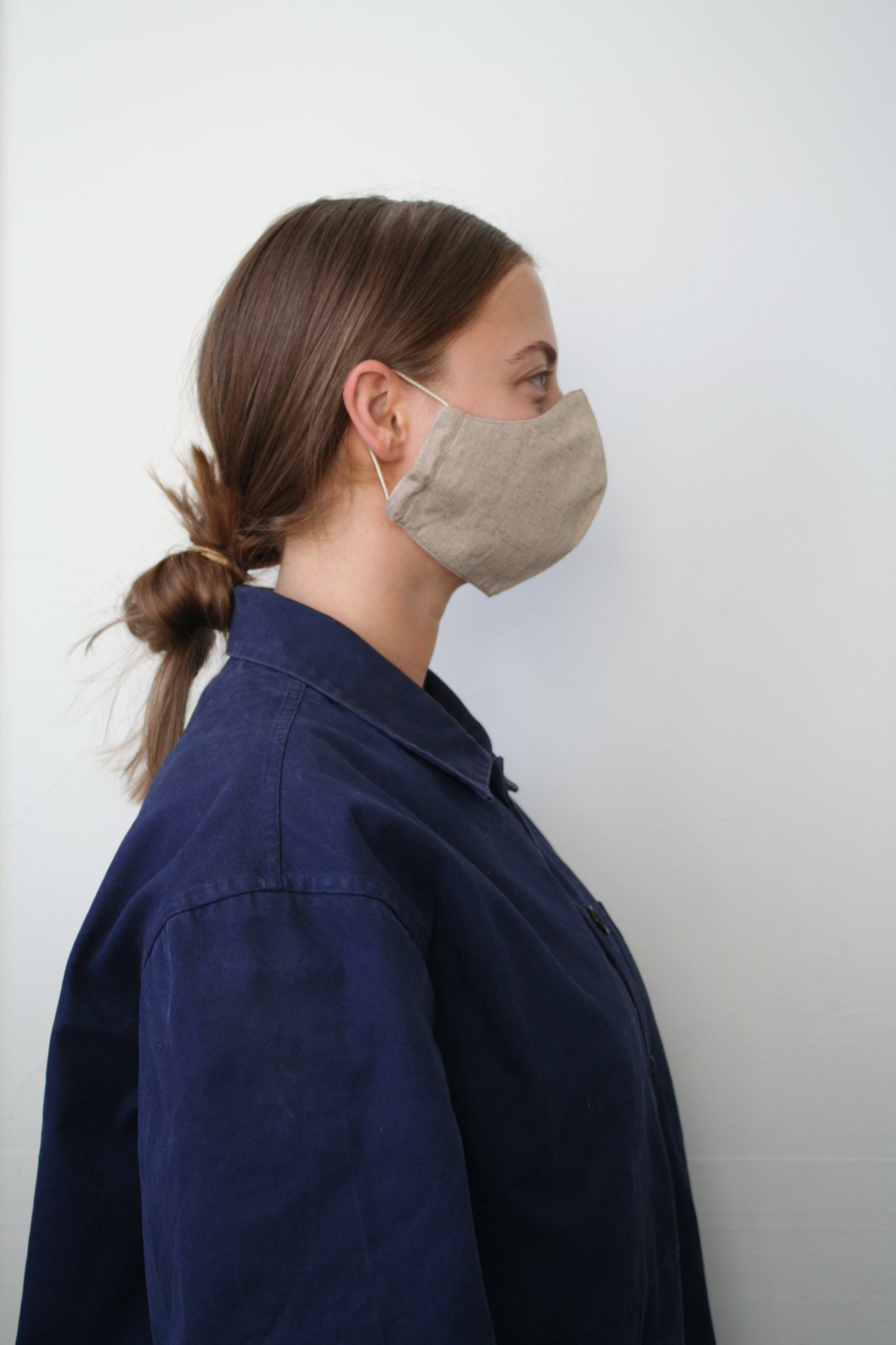 side view of a woman wearing a light brown face mask